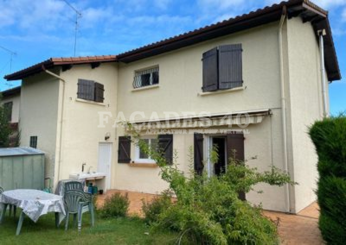 Maison avec fenêtres et volets, jardin, table et chaises.