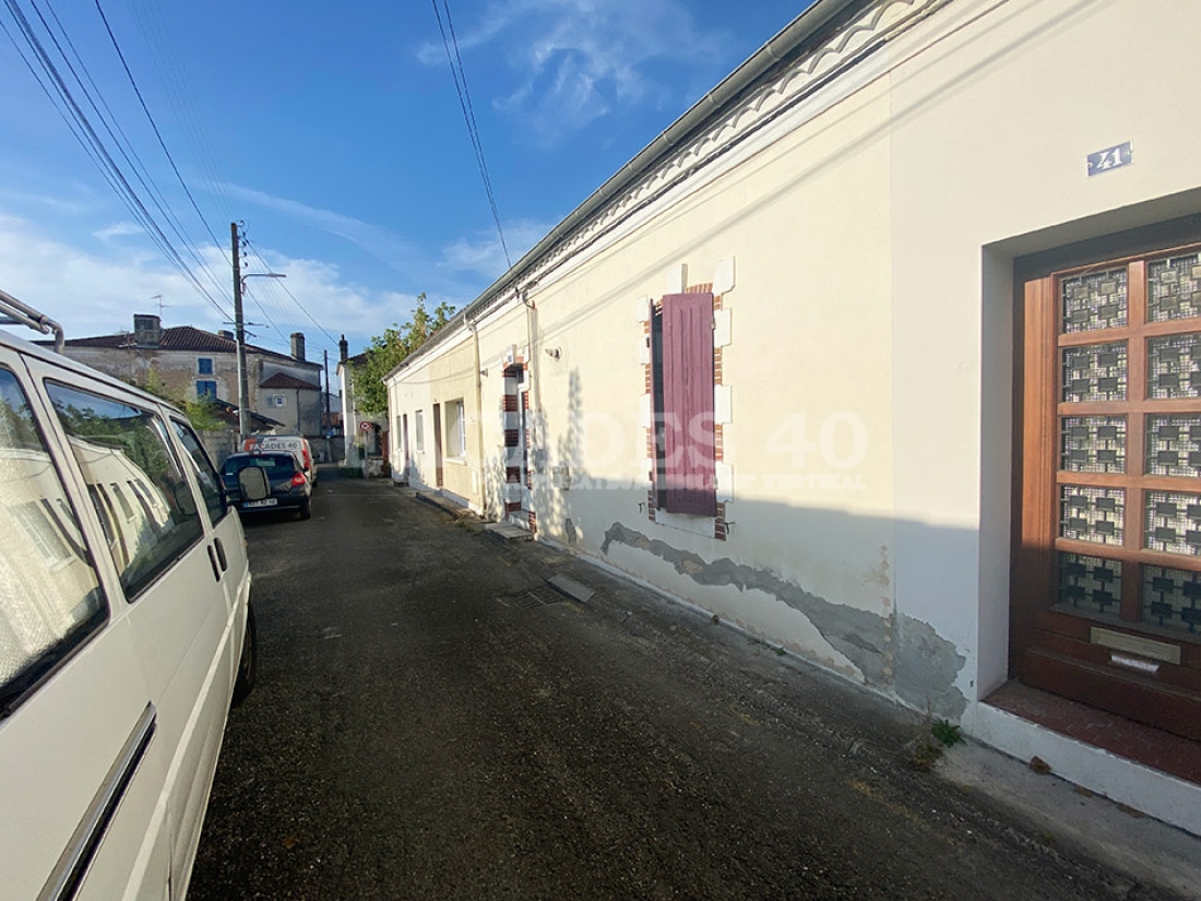 Photo d’ensemble des façades avec en pieds de mur bien visible les zones cloquées de l’enduit.