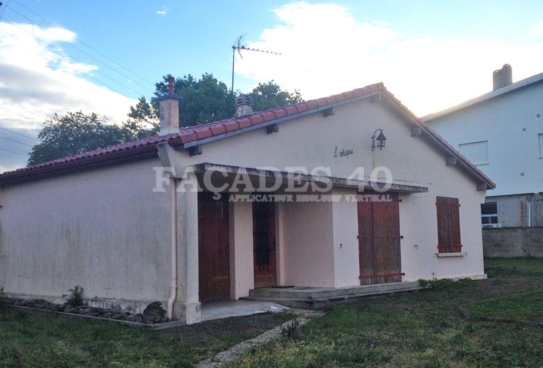 Maison blanche avec portes rouges et toiture en tuiles rouges.