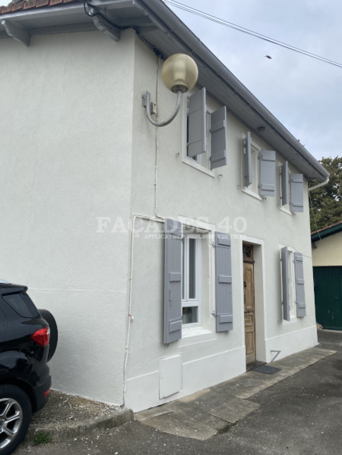 Maison blanche avec volets gris, voiture noire, lampadaire. Façades 40