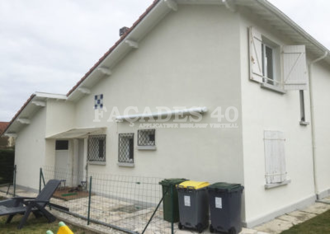 Maison blanche avec fenêtres et poubelles.