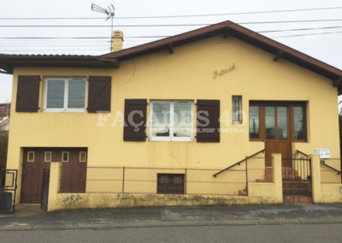 Maison jaune avec volets marron et porte marron.