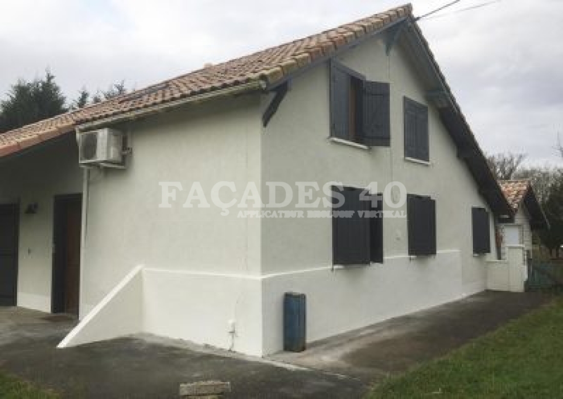 Maison blanche avec volets noirs et climatiseur.