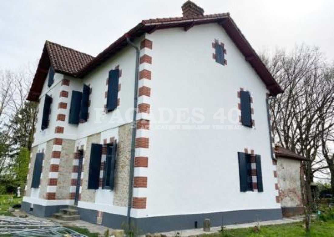 Maison à deux étages avec façades à rayures rouges et blanches.